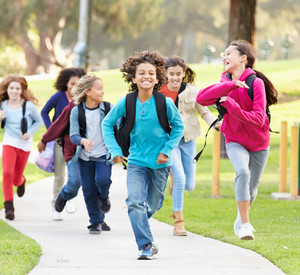 Group Of Children Running Along Path Towards Camera In Park