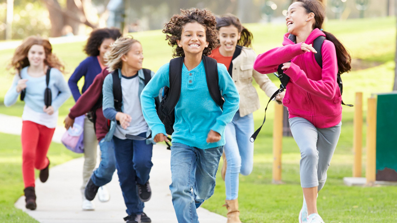 Group Of Children Running Along Path Towards Camera In Park