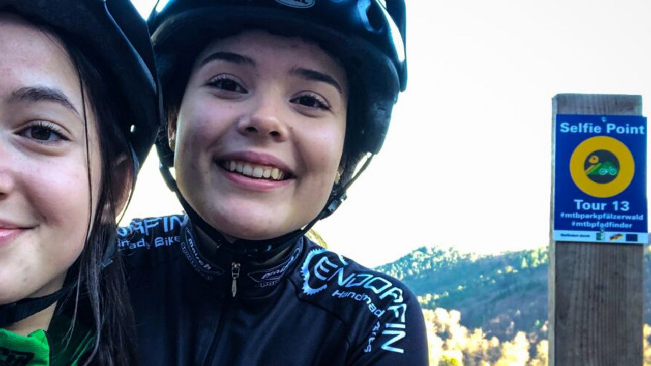 Zwei junge Mountainbikerinnen machen ein gemeinsames Selfie vor einem Selfiepoint